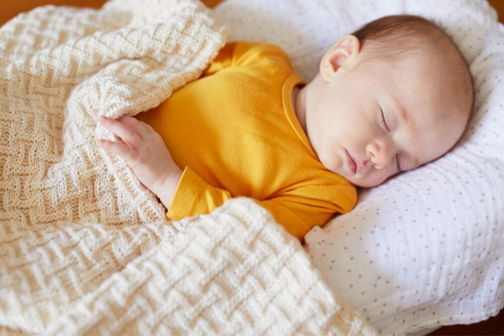 baby sleeping with a knitted blanket